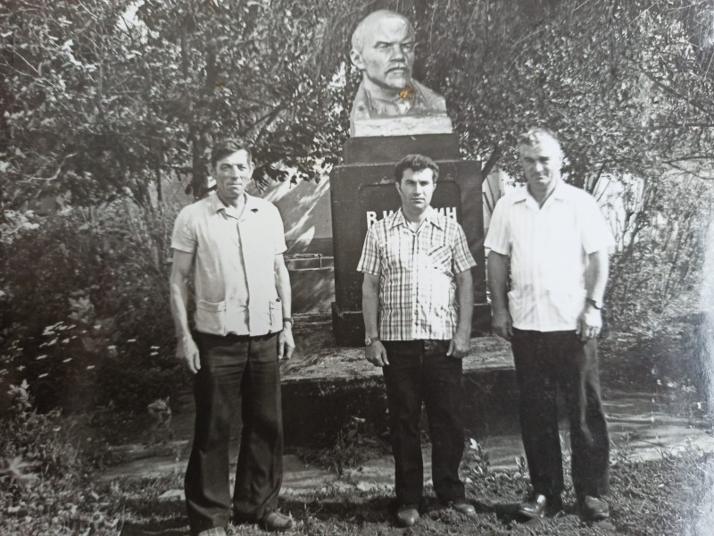 Фотографія трьох чоловіків біля пам'ятника Леніну