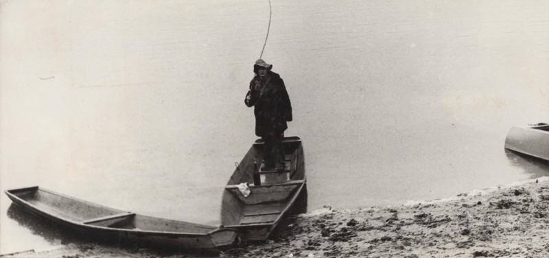 Фотографія. В. Івасюк. Стоїть в човні на березі річки.