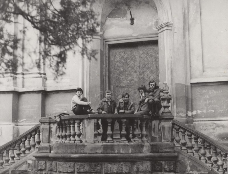 Фотографія. В. Івасюк з хлопцями сидять на кам’яних перилах.