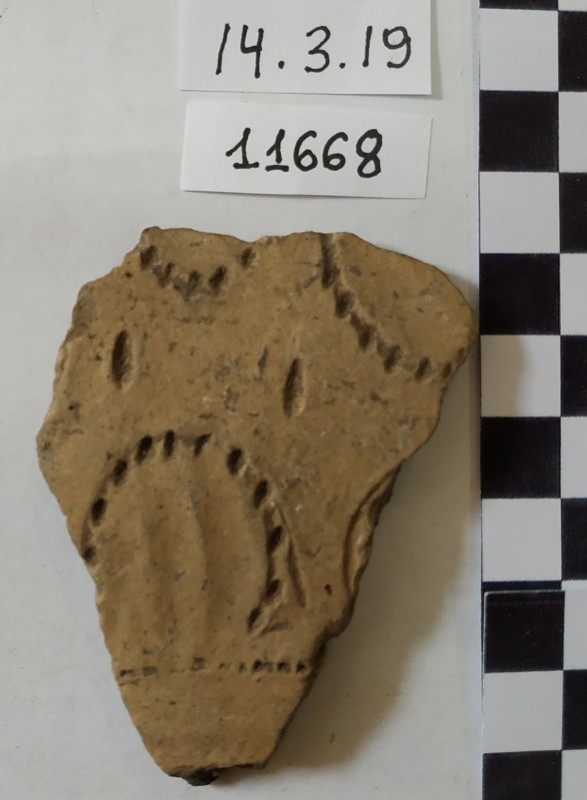 Фрагмент стінки ліпного сіроглиняного посуду жовтого кольору зовні.