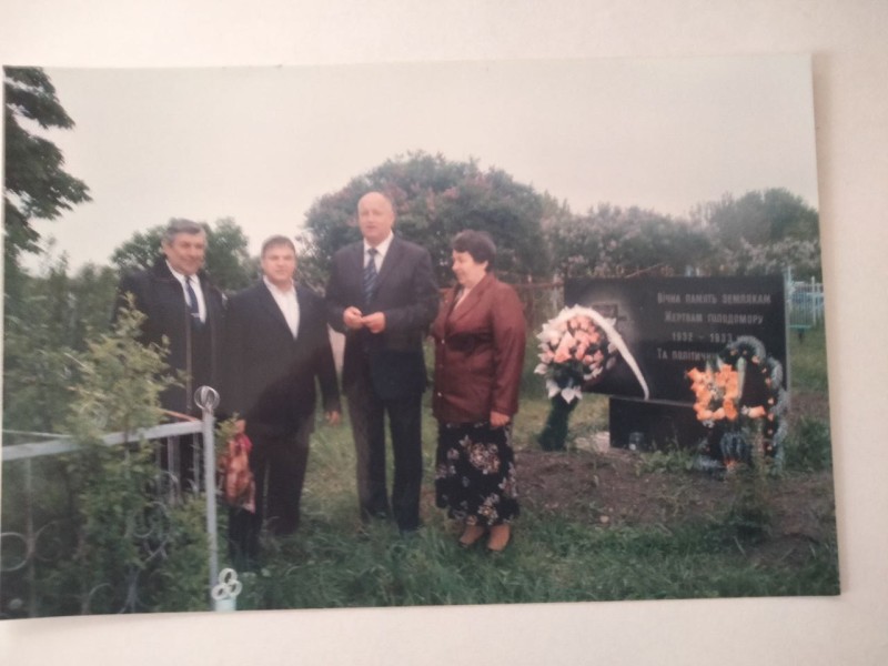 Фото. Біля меморіальної плити жертвам голодомору с. Бреусівка з ліва направо - шкільний товариш Олеся Волі Григорій Сердюк, брат Михайло О.В., ГОЛОВА СІЛЬРАДИ ГАЛИНИ МАЛИК