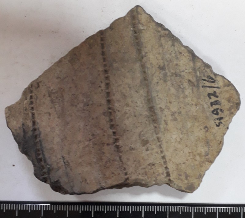 Фрагмент стінки ліпного сіроглиняного посуду, жовтого кольору зовні.