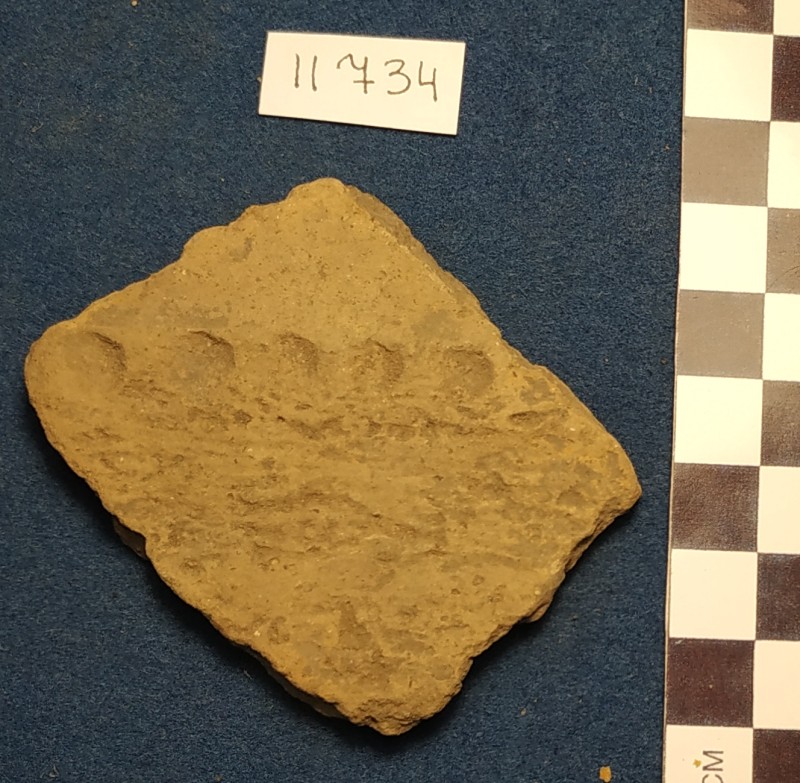 Фрагмент стінки ліпної сіроглиняної посудини жовтого кольору ззовні