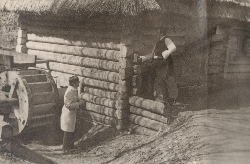 Фотографія. В. Івасюк розмовляє з чоловіком, що стоїть біля дерев’яної хати. 1974-1975 роки.