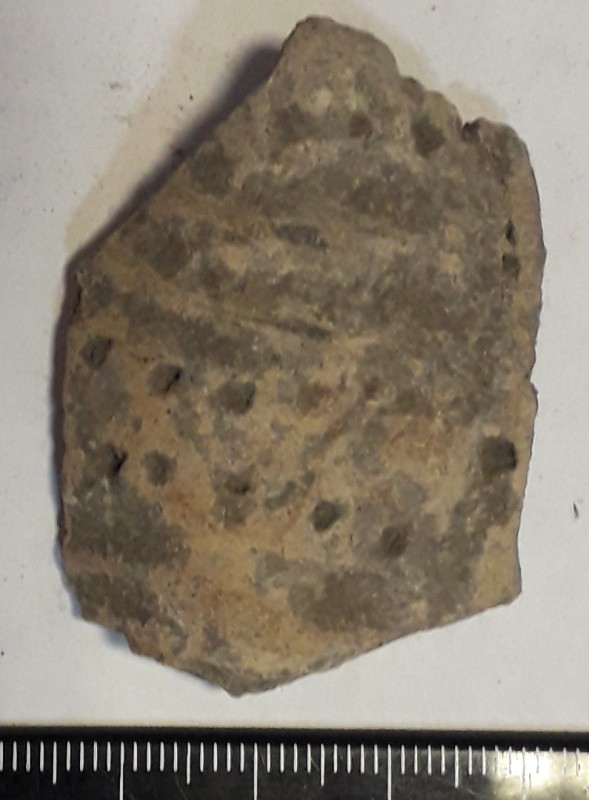 Фрагмент стінки ліпної сіроглиняної посудини жовтого кольору назовні.