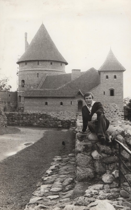 Фотографія. В. Івасюк сидить на кам’яному мурі, позаду будинки Тракайського замку. Вільнюс. Липень 1978 року.