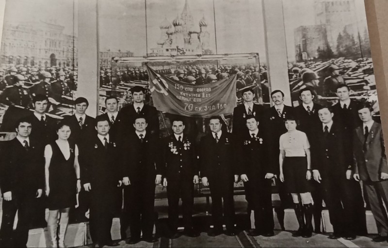 Переможці соціалістичного змагання, присвяченого гідній зустрічі 30-річчя Перемоги, біля розгорнутого Прапора Перемоги.