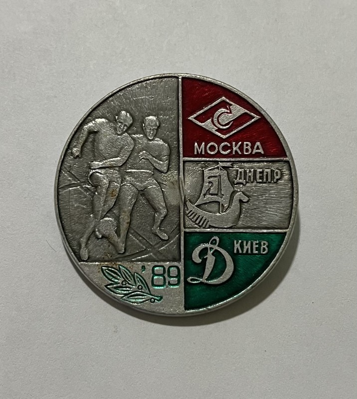 Значок металевий круглої форми з гладким тонким бортом.